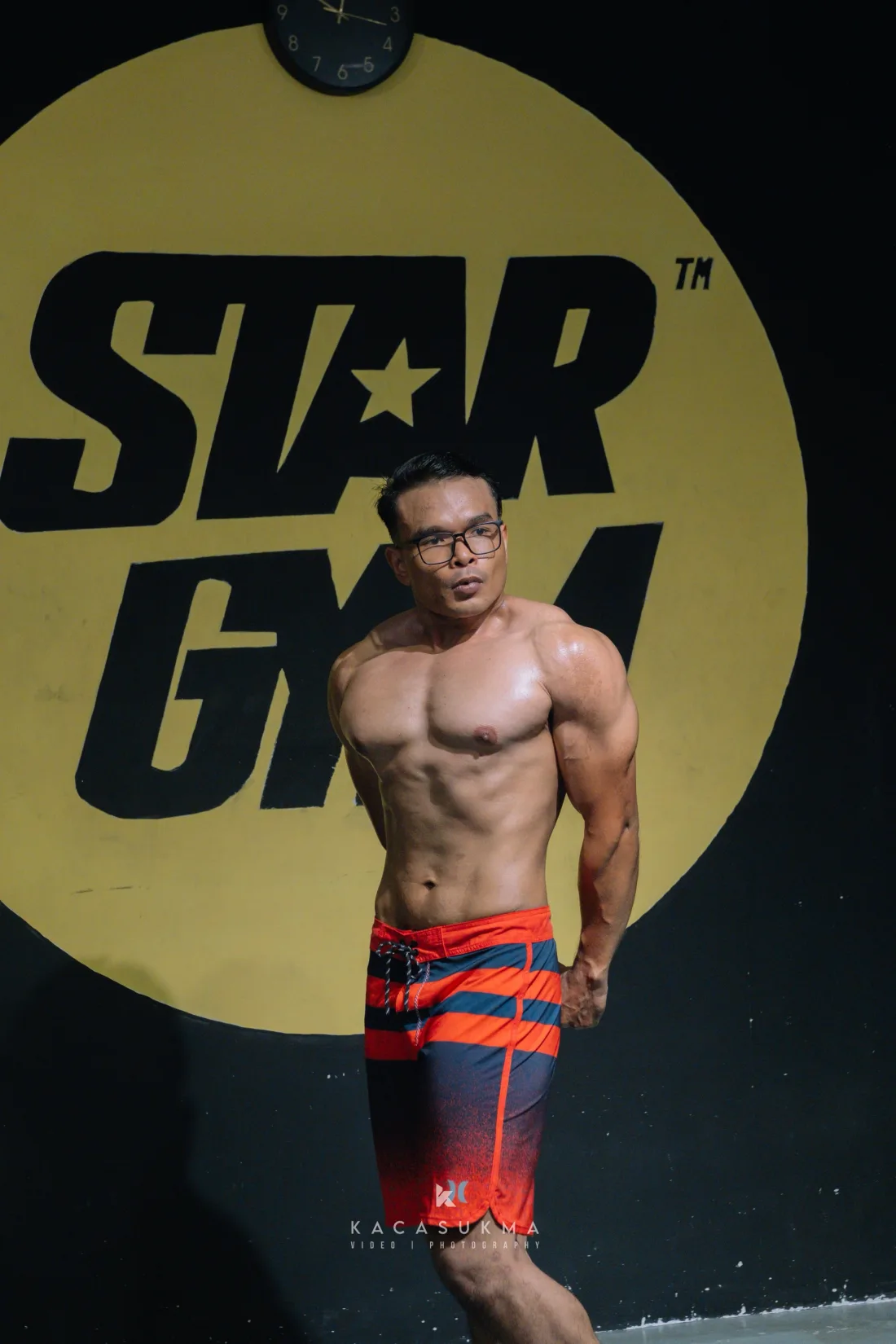 Competitor posing on stage in front of the Star Gym backdrop